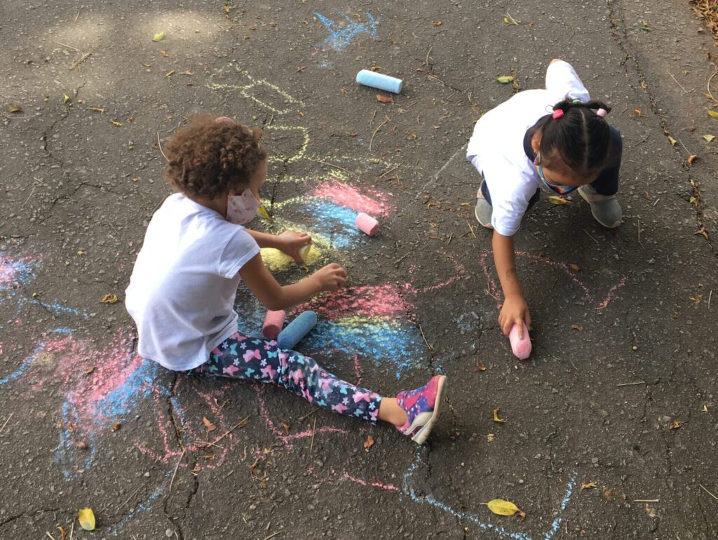 Crianças desenhando no chão com giz colorido no local da intervenção urbana - EMEI Dona Ana Rosa de Araújo - SP.